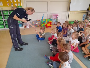 w sali przedszkolnej policjantka rozdaje dzieciom odblaski