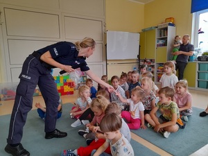 w sali przedszkolnej policjantka rozdaje dzieciom odblaski