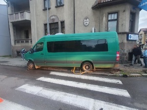 na ulicy na przejściu dla pieszych znajduje się uszkodzony zielony mercedes sprinter. Auto stoi na zgniecionych barierkach drogowych