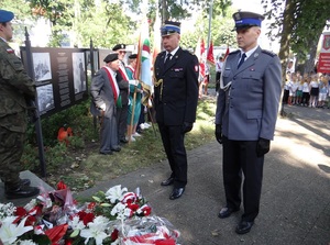 przed pomnikiem Zesłańców Sybiru stoją obok siebie przedstawiciel Straży Pożarnej i Policji