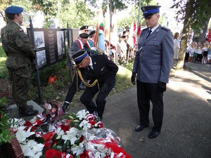 Komendant Powiatowy Państwowej Straży Pożarnej składa kwiaty pod pomnikiem Zesłańców Sybiru. Obok niego stoi Zastępca Naczelnika Wydziału Prewencji KPP w Lęborku