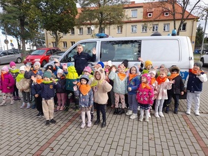 na tle radiowozu stoi policjantka oraz grupa przedszkolaków