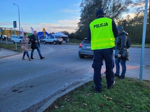 policjant w kamizelce odblaskowej przekazuje pieszemu element odblaskowy