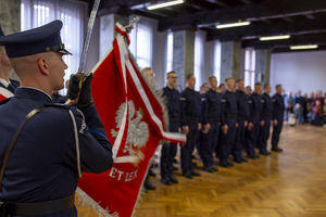 na auli wystawiony jest sztandar. Policjant z pocztu sztandarowego unosi szablę. W rzędzie stoją policjanci