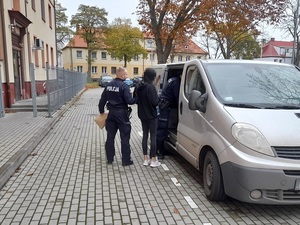 policjant wprowadza do nieoznakowanego radiowozu kobietę