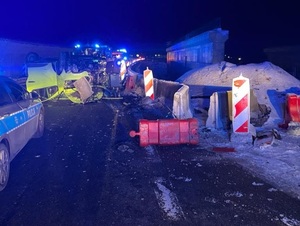 pora wieczorowa. Miejsce zdarzenia drogowego. Na zwężonym remontowanym odcinku drogi na dachu leży pojazd typu bus przy którym znajduja się służby ratunkowe i policyjny radiowóz