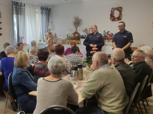 w sali Gminnego Ośrodka Kultury i Sportu w Wicku policjantka i policjant rozmawiają z seniorami