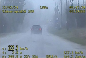 zapis videorejestratora policyjnego radiowozu. Na ekranie widać samochód na terenie zabudowanym. Zapis wskazuje prędkość 122 km/h, z jaką auto się porusza, datę 12.02.2024, godz. 08:47