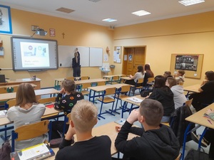 w klasie szkolnej policjantka pisze na tablicy wady i zalety internetu