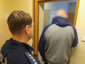 do celi wchodzi zatrzymany mężczyzna. Za nim stoi policjant służby dyżurnej