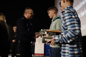 policjant w mundurze wręcza nagrodę dzieciom
