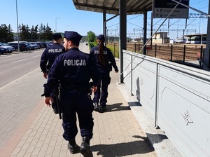 patrol składający się z trojga policjantów: dwóch policjantów i policjantki idzie w kierunku przejścia podziemnego przy dworcu PKP