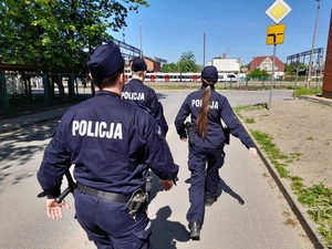 patrol składający się z trojga policjantów: dwóch policjantów i policjantki idzie w kierunku dworca PKP