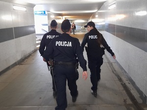 patrol składający się z trojga policjantów: dwóch policjantów i policjantki idzie przejściem podziemnym dworca PKP