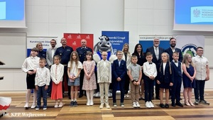 Na scenie stoją dzieci ze szkół podstawowych w towarzystwie Komendanta Wojewódzkiego Policji w Gdańsku, innych policjantów, przedstawicieli organizatorów gali oraz żywej maskotki pomorskich policjantów - słonika POPO