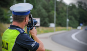 stojący przy drodze policjant ruchu drogowego, którzy mierzy prędkość pojazdów ręcznym miernikiem