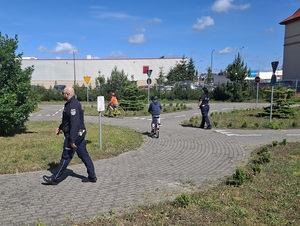 miasteczko ruchu drogowego, po którym jeżdżą dzieci na rowerach i chodzą policjanci ruchu drogowego