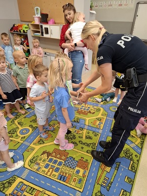 w sali przedszkolnej policjantka zakłada dzieciom kajdanki