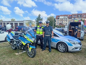 przy radiowozie stoi policjant ruchu drogowego i inspektor ITD. Za nimi przy otwartych tylnych drzwiach busa stoi policjantka. Przed nimi stoi policyjny motocykl