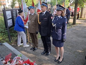 przedstawiciel wojska, straży pożarnej i policji stoją przed pomnikiem zesłańców sybiru