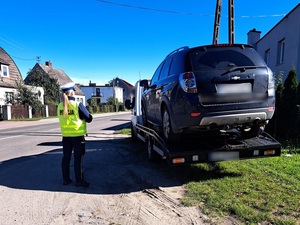 przed lawetą na której znajduje się osobowy chevrolet stoi policjantka ruchu drogowego