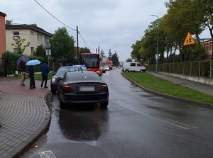 miejsce zdarzenia drogowego. Tuż za łukiem drogi przy lewej stronie jezdni znajdują się dwa samochody zderzone ze sobą czołowo. Za nimi stoi policyjny radiowóz