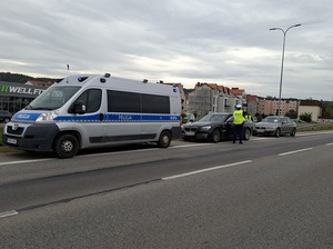 na poboczu drogi K6 w Lęborku stoi oznakowany policyjny radiowóz. Za nim znajduje się czarne bmw, za bmw nieoznakowany radiowóz. Przy bmw stoi policjant ruchu drogowego