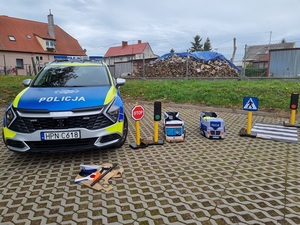 na placu stoi oznakowany radiowóz. Obok stoją zabawkowe znaki drogowe i autochodziki (radiowóz i autobus)