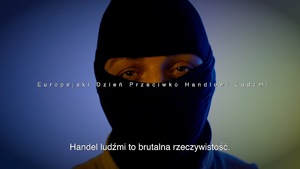 mężczyzna w kominiarce i biały napis o treści &quot;Europejski Dzień Przeciwko Handlowi Ludźmi&quot;. &quot;Handel ludźmi to brutalna rzeczywistość&quot;