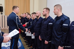 W auli Szkoły Policji w Słupsku Komendant wręcza dyplomy stojącym w rzędzie policjantom