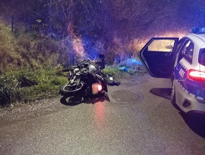 pora nocna. Na poboczu leży przewrócony motocykl. Obok stoi policyjny radiowóz