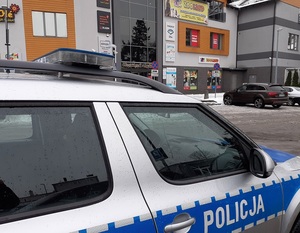 oznakowany policyjny radiowóz przed centrum handlowym