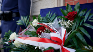 wieniec z kwiatów. W tle policjant