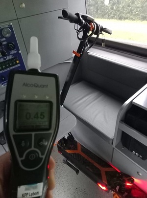 wewnątrz radiowozu stoi hulajnoga elektryczna. Na pierwszym planie znajduje się alkotest z wyświetlonym wynikiem badania 0,55 mg/l