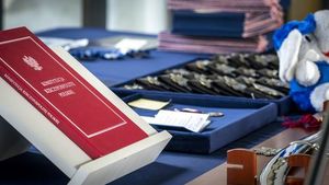 na stole wyłożonym granatowym obrusem leży Konstytucja RP, policyjne odznaki i medale