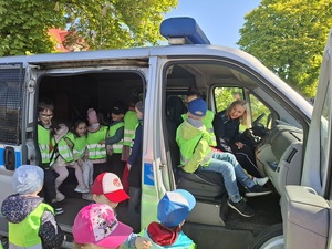 grupa przedszkolaków w policyjnym radiowozie. Na miejscu kierowcy siedzi policjantka