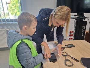 policjantka przykłada palec przedszkolaka do gąbki z tuszem