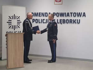 w auli lęborskiej komendy policji przy  Komendant Wojewódzki Policji w Gdańsku, trzymający w ręce rozkaz personalny ściska dłoń Komendanta Powiatowego Policji w Lęborku.