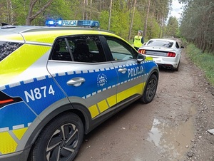 policjant przy radiowozie kontroluje auto, zdjęcie urządzenia do pomiaru