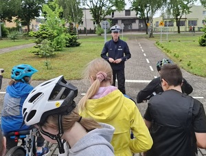 na terenie miasteczka ruchu drogowego przed grupą 10-latków stoi policjant ruchu drogowego