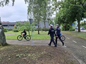 na terenie miasteczka ruchu drogowego dwaj policjanci z drogówki obserwują przejazd rowerami dwojga młodych rowerzystów