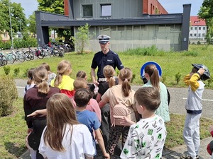 na terenie miasteczka ruchu drogowego policjant ruchu drogowego rozmawia z grupą 10-latków
