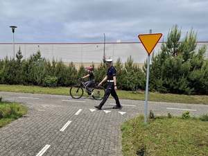 na terenie miasteczka ruchu drogowego policjant z drogówki obserwuje dziewczynkę jadącą rowerem
