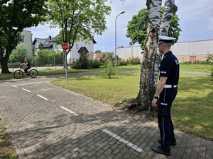na terenie miasteczka ruchu drogowego policjant z drogówki obserwuje dziewczynkę jadącą rowerem