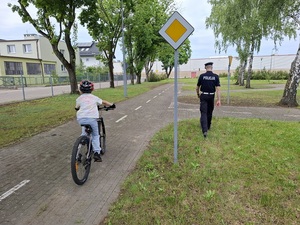 na terenie miasteczka ruchu drogowego policjant z drogówki obserwuje dziewczynkę jadącą rowerem