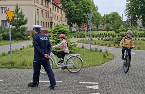 policjanci z młodymi rowerzystami na miasteczku ruchu drogowego