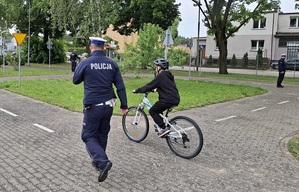 policjanci z młodymi rowerzystami na miasteczku ruchu drogowego