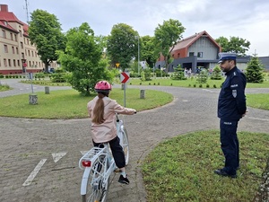 policjanci z młodymi rowerzystami na miasteczku ruchu drogowego
