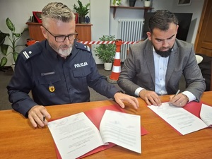 przy stole siedzą Komendant Powiatowy Policji w Lęborku i Starosta Lęborski, którzy podpisują dokumenty przekazania sprzętu