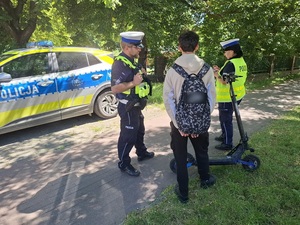 na drodze dla rowerów policjant i policjantka kontrolują młodego mężczyznę, stojącego przy hulajnodze elektrycznej